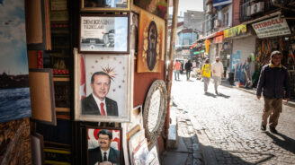 People passing by portraits of Turgut Ozal and Recep Tayyip Erdogan, current president of Turkey, in a street of Istanbul.